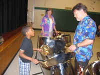 Musician Ted Canning works with a student on playing the steel drums.