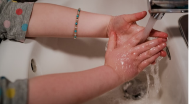 girl washing hands under running water