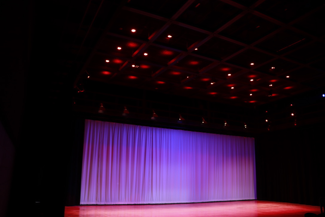 Picture of the Black Box Theatre, showing a purple curtain at the back of the theatre and spotlights above