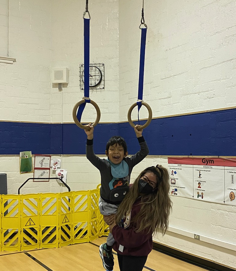 student hanging from the paralel gymnastics rings