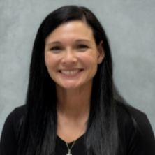 Woman with long black hair wearing a black shirt and a cross necklace. She is smiling at the camera.