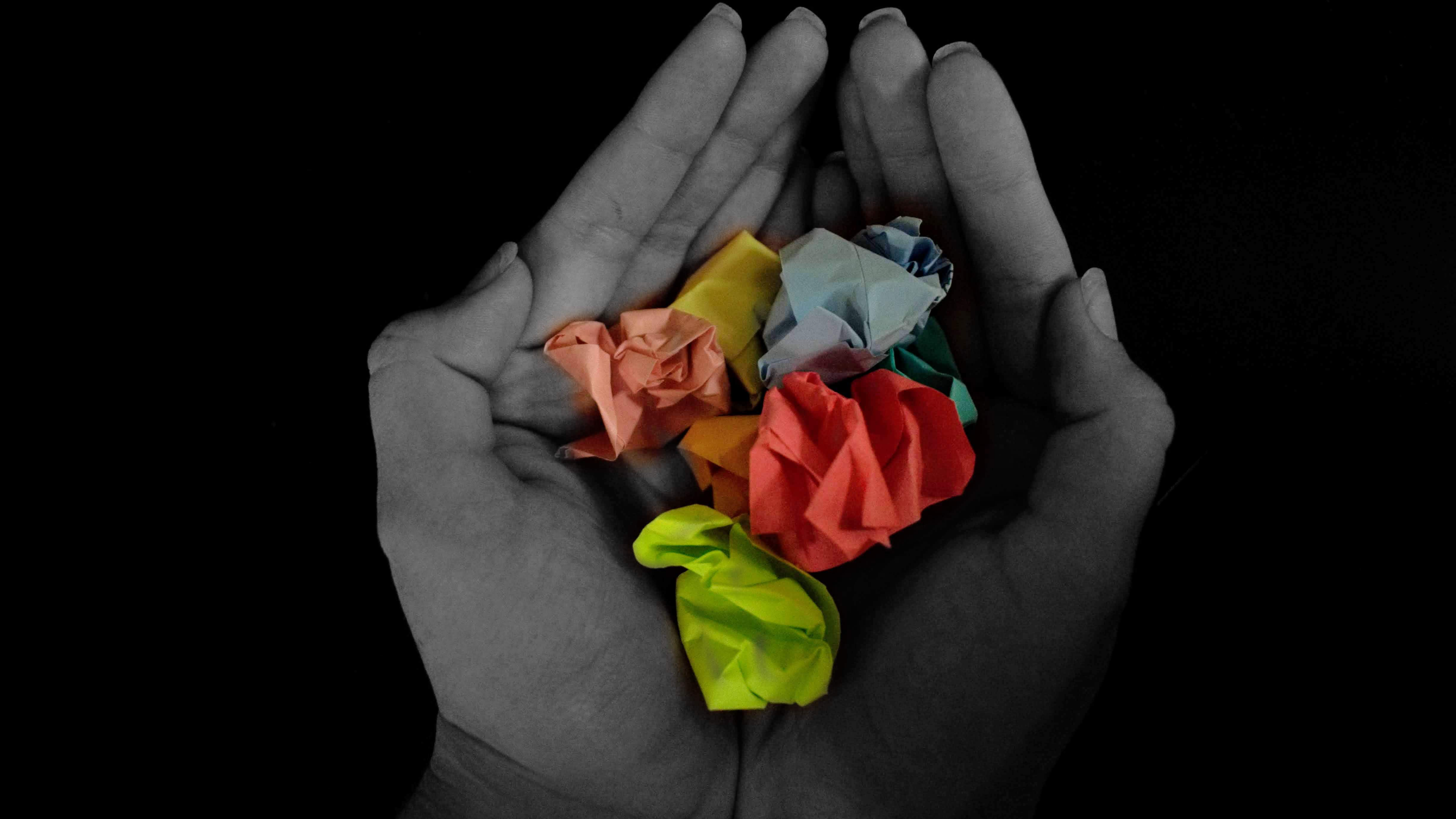 Picture of hands holding crumpled colorful pieces of paper