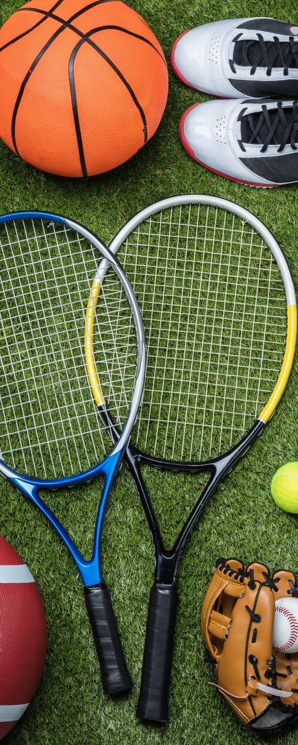 Picture of assorted sports equipment on green grass (tennis racket, basketball, baseball and glove)