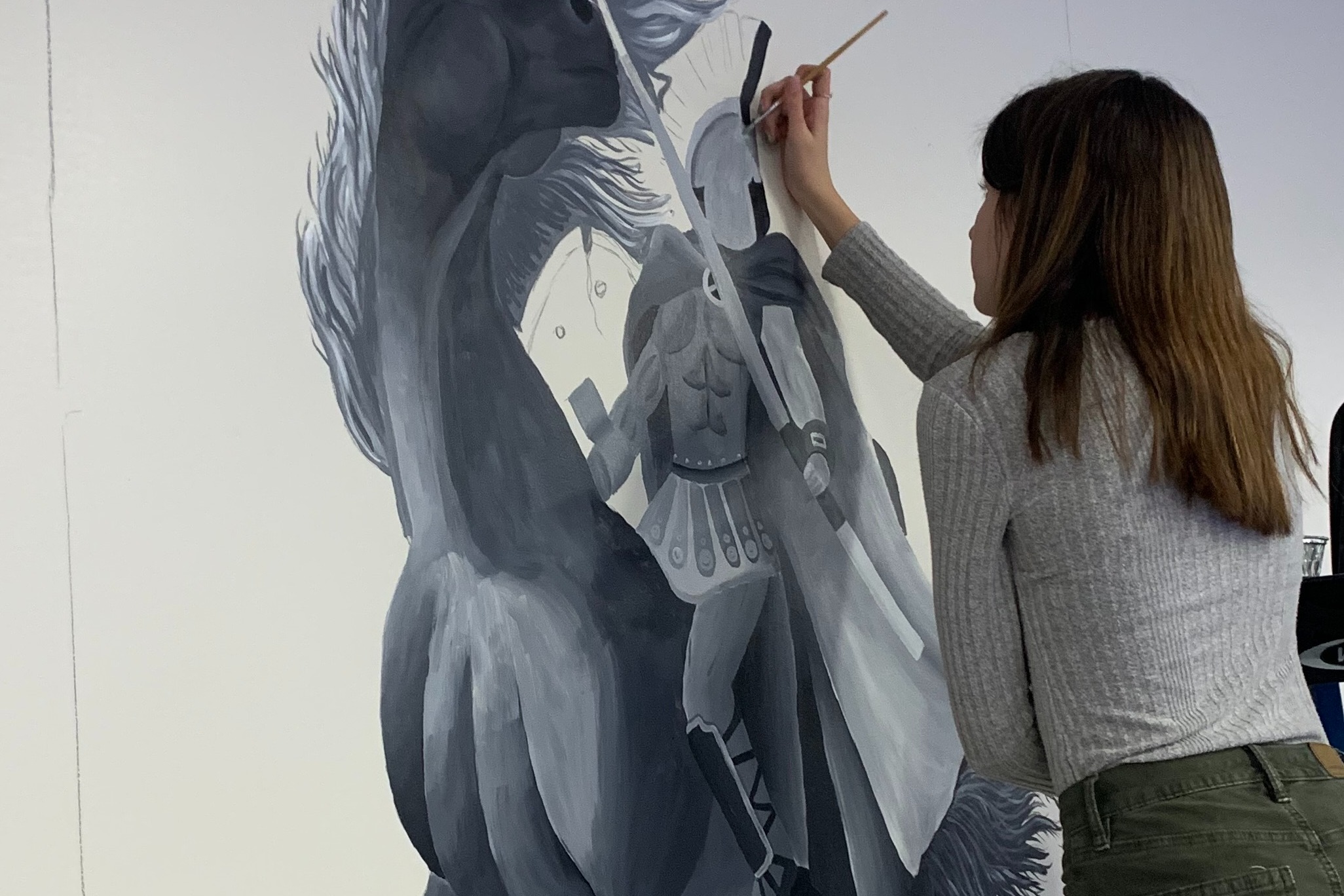 Picture of student artist painting a mural