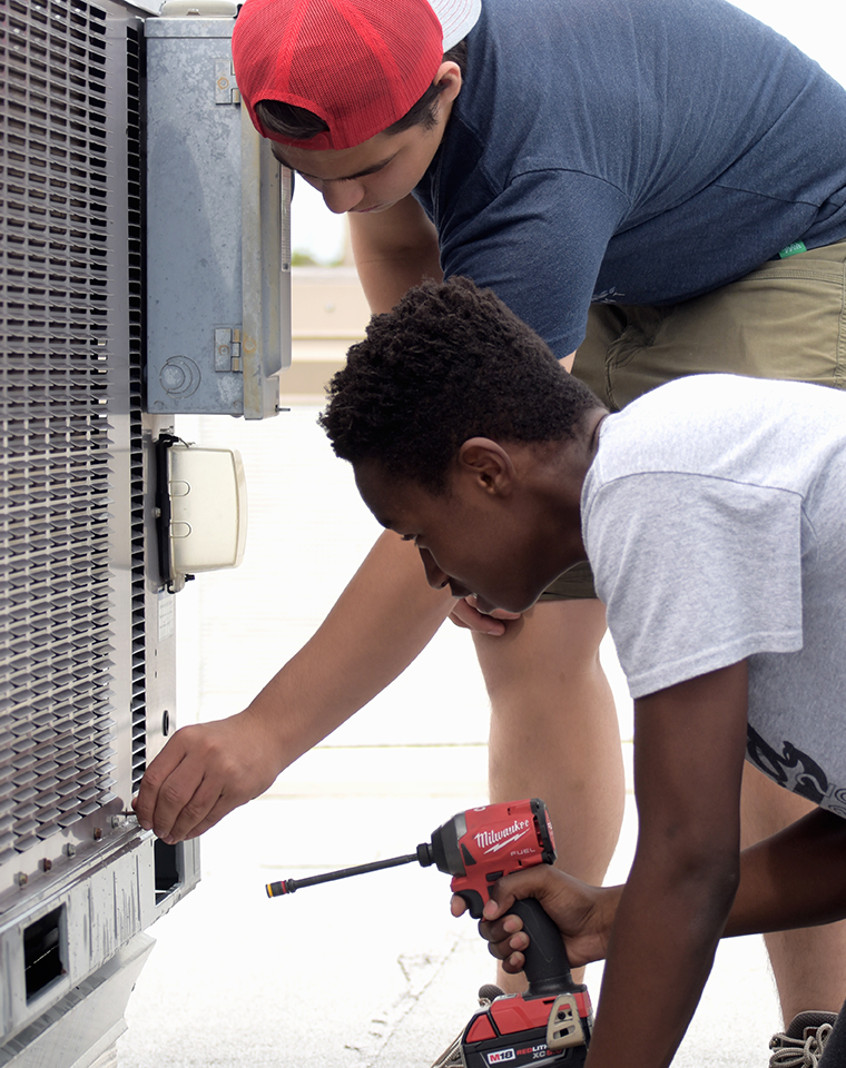 Students on the CTE Summer Workforce work to repair a rooftop AC unit