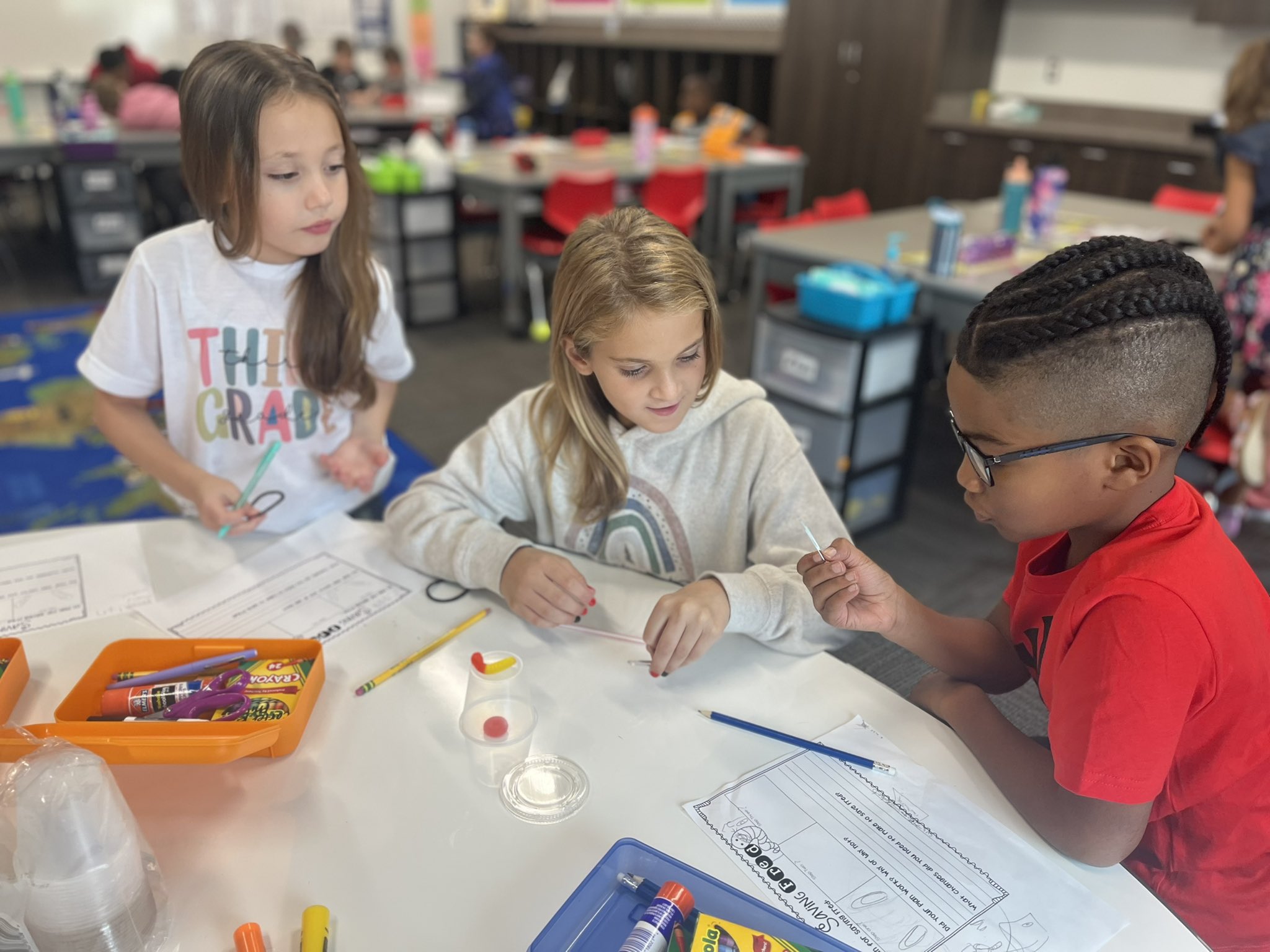 three students work together at their classroom table
