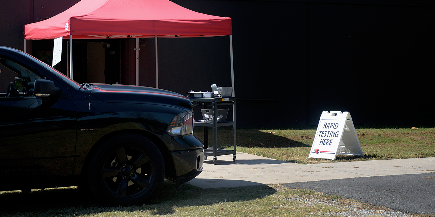 Car sits next to tent at drive-thru testing site