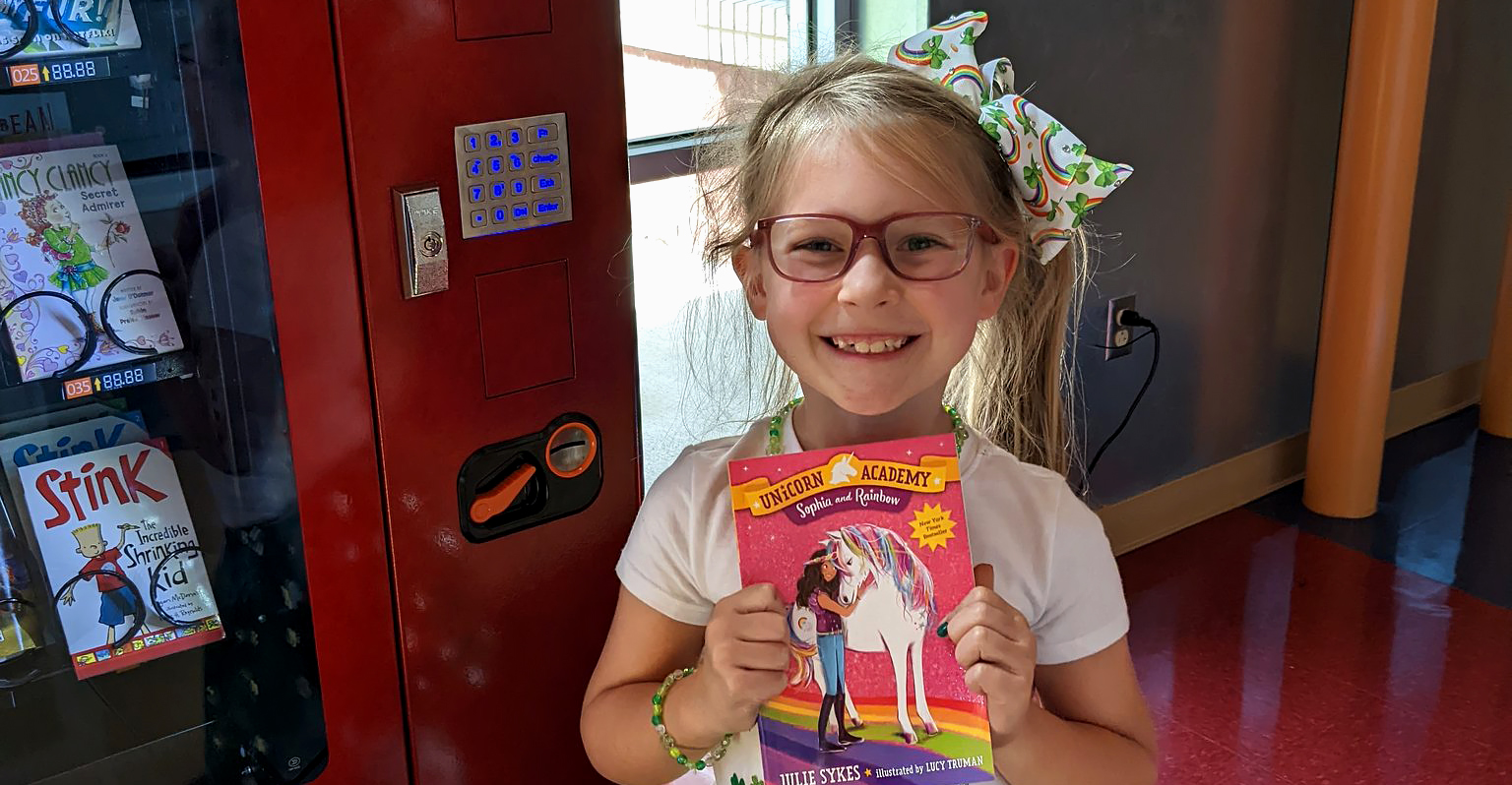 Girl receiving a book from the book vending machine