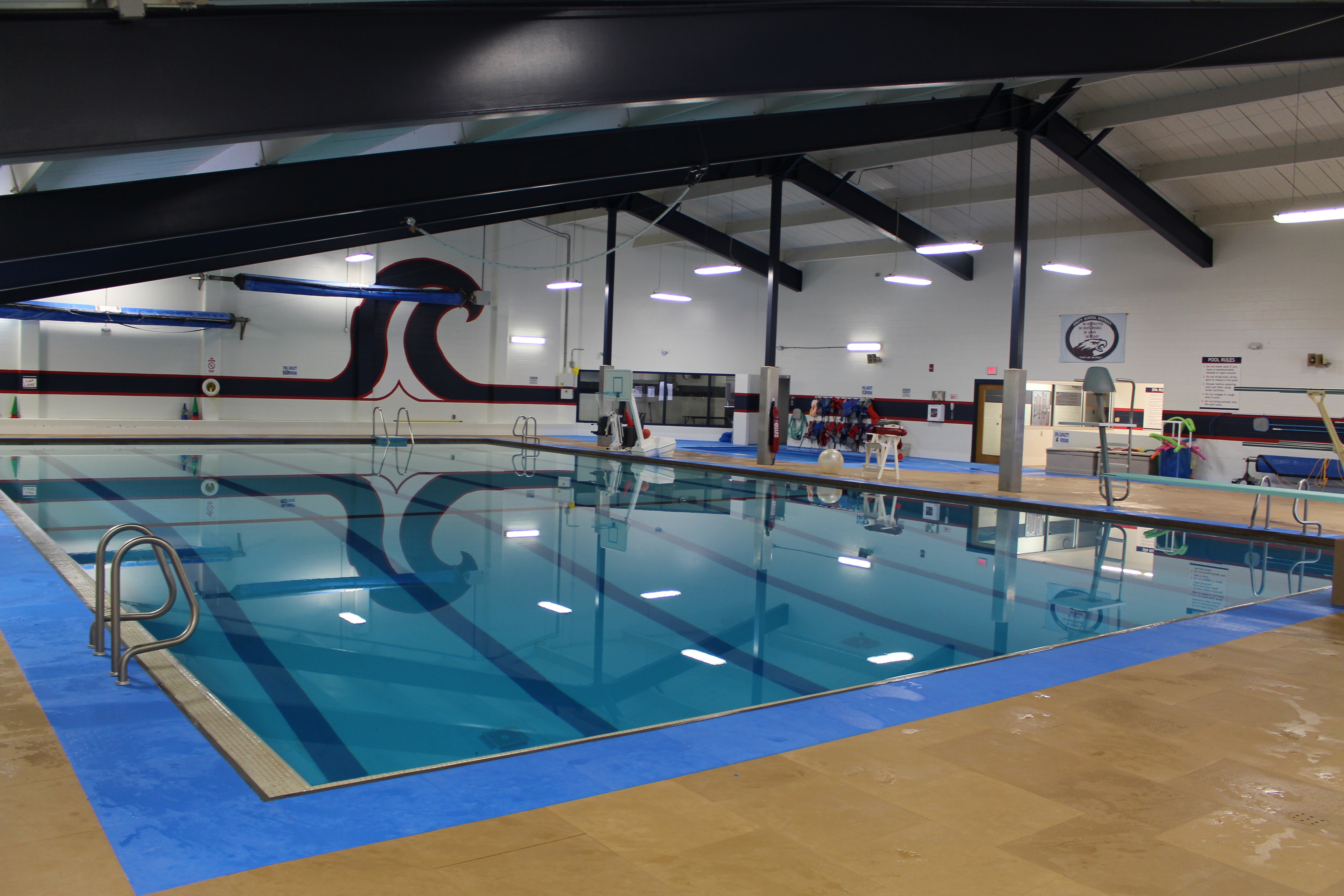 Large indoor swimming pool with clear blue water and blue pool deck