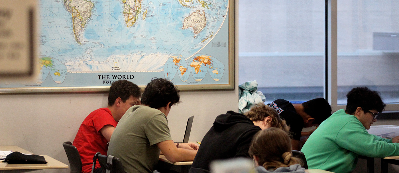 A view of a classroom of students with a world map on the wall