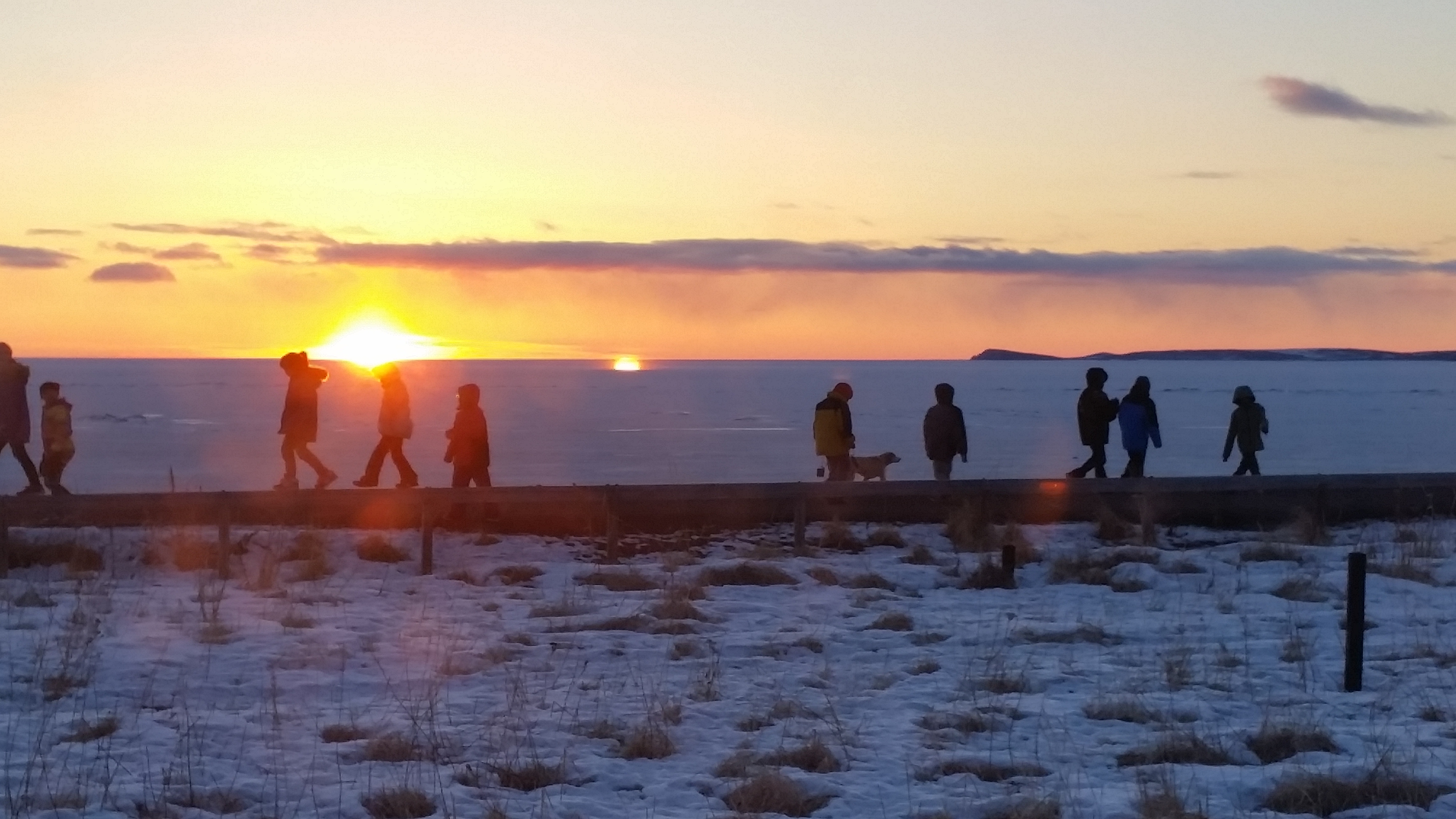 Students walking along ocean at sunset