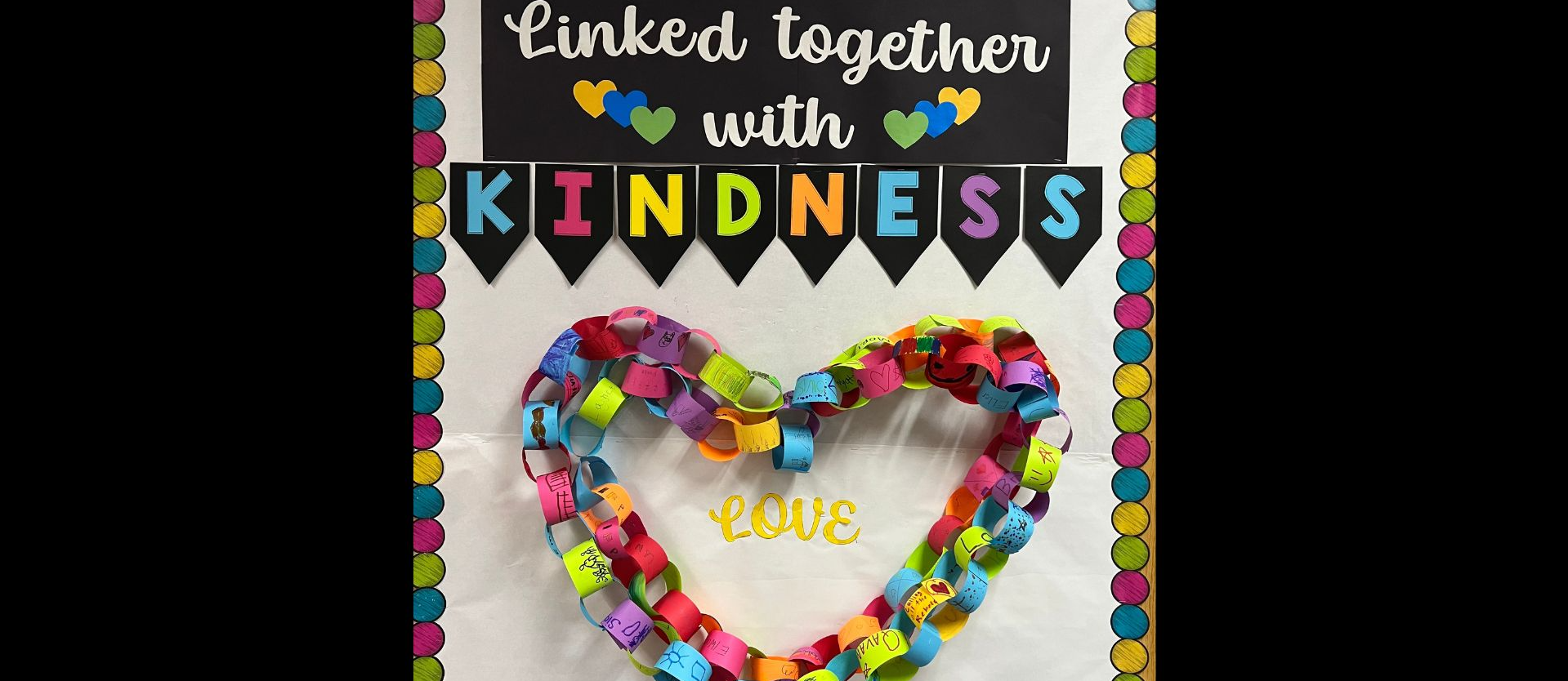 Words Linked together with kindness, a heart made out of colored paper chains around the word Love.