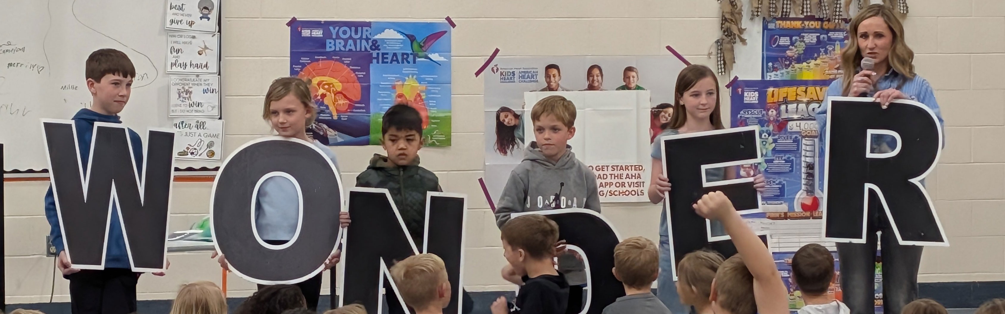Students and principal holding up letters that spell "WONDER".