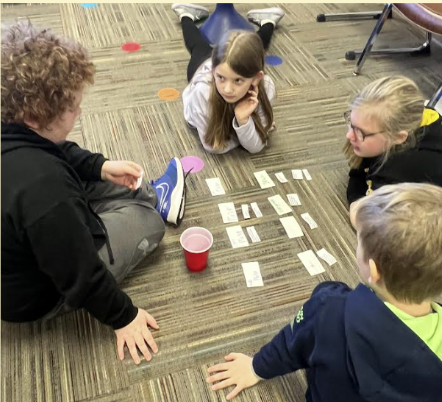 STEM Students sitting on the floor playing cards 