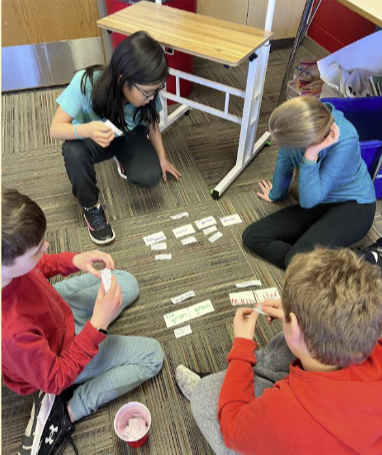 STEM students sitting on the floor playing cards 