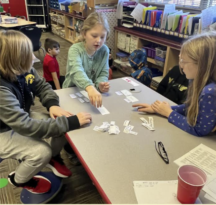 STEM Students sitting at a desk playing cards 