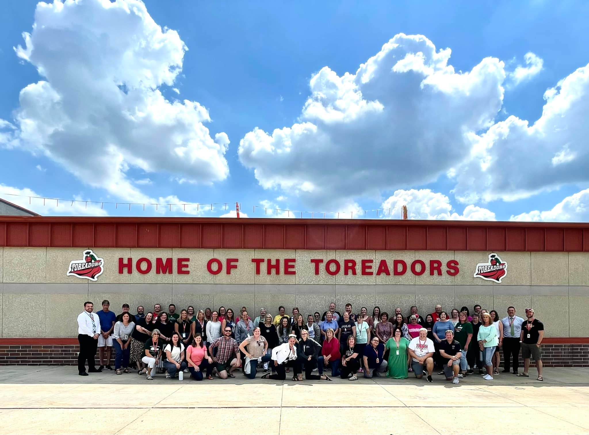 Teachers standing in front of the Boone High School under the Home of the Toreadors sign