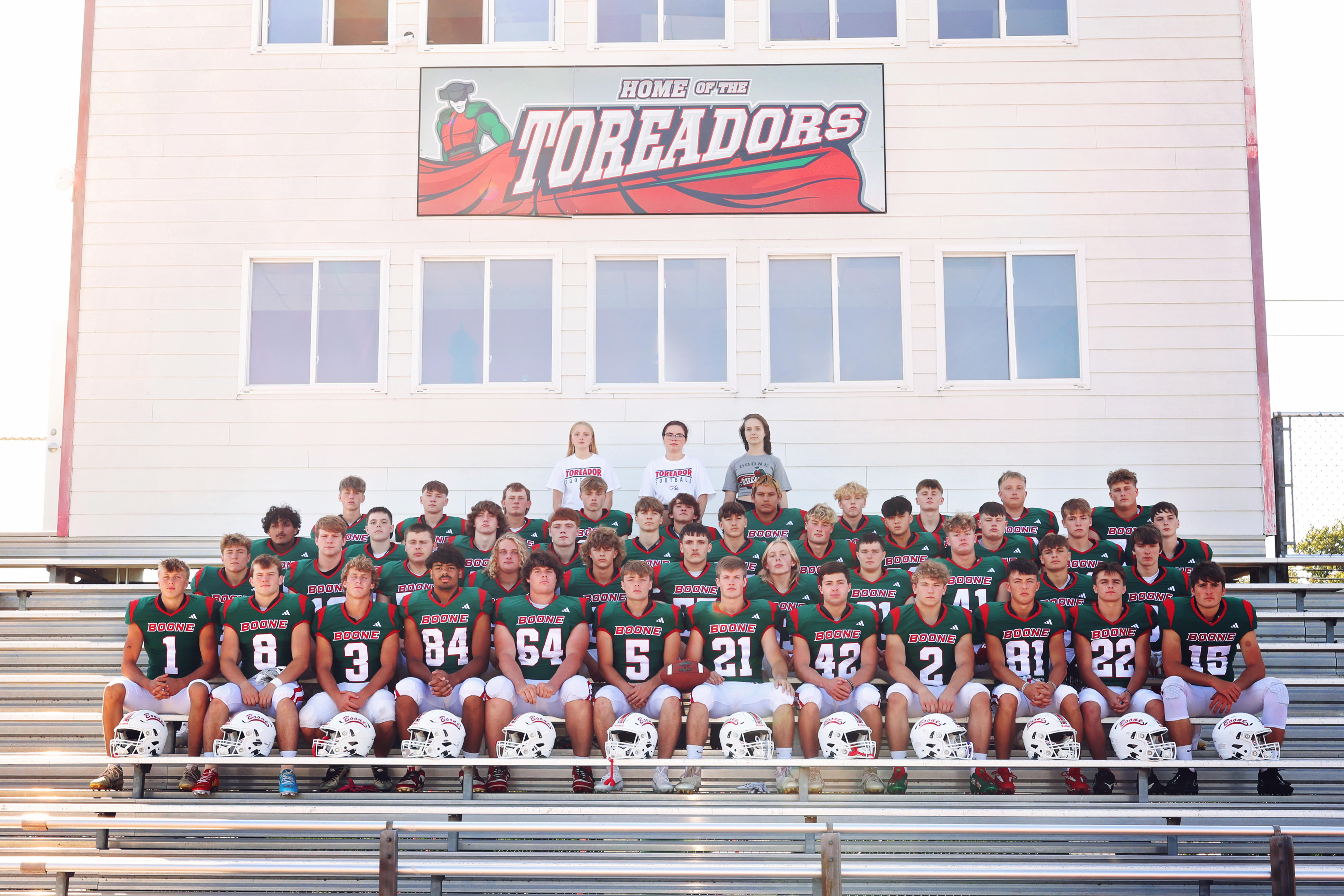 Football players on the bleachers at the football field with the scoreboard 