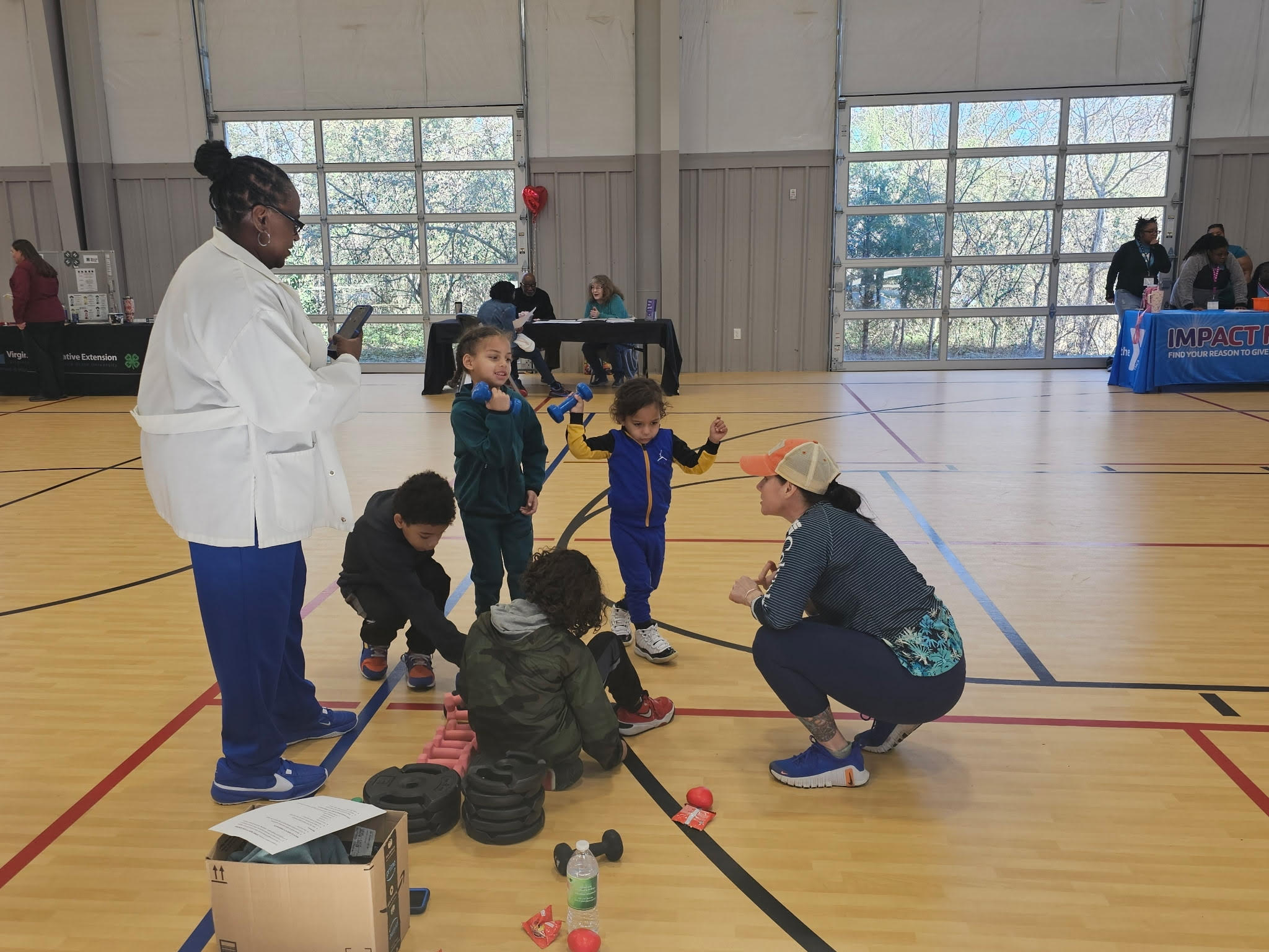 students lifting small weights during a healthy heart event. setting is in an indoor gym.