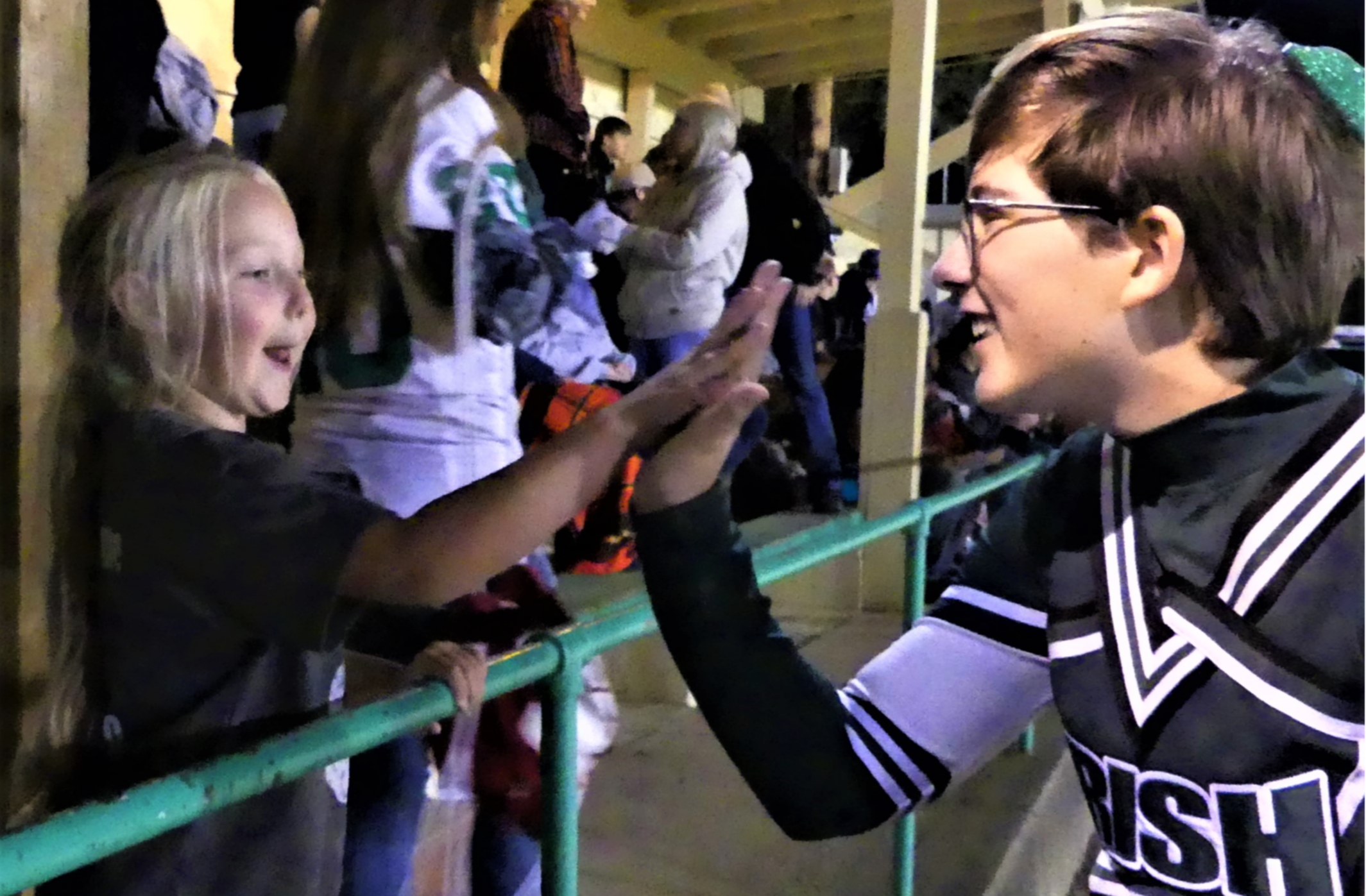 Cheerleader with elementary student at football game.