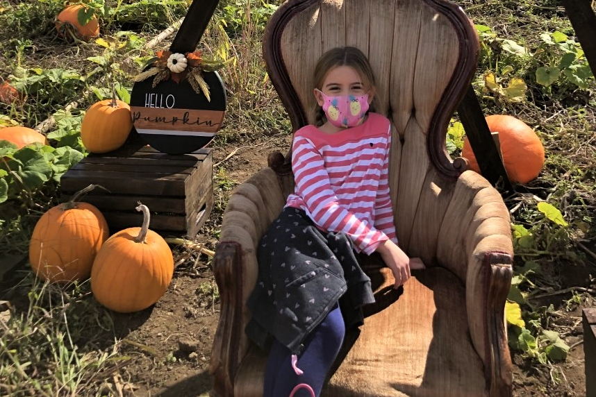 Student sitting at a pumpkin patch