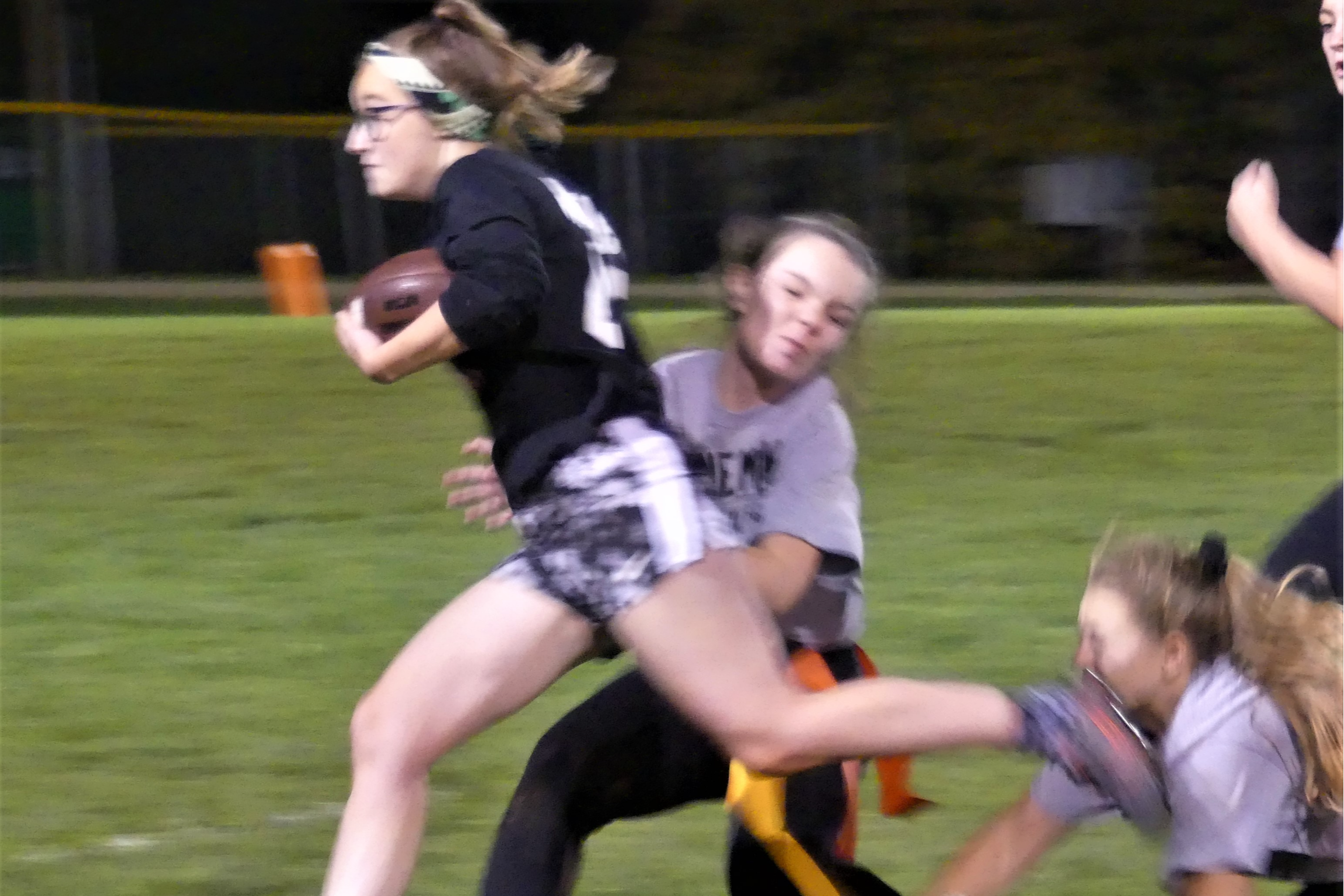 Homecoming Powder Puff Game. Team grabs for the flags of the running back. The running back's left foot makes contact with a player on the opposing team.