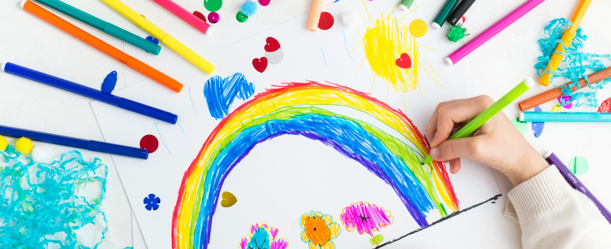 child drawing rainbow with markers