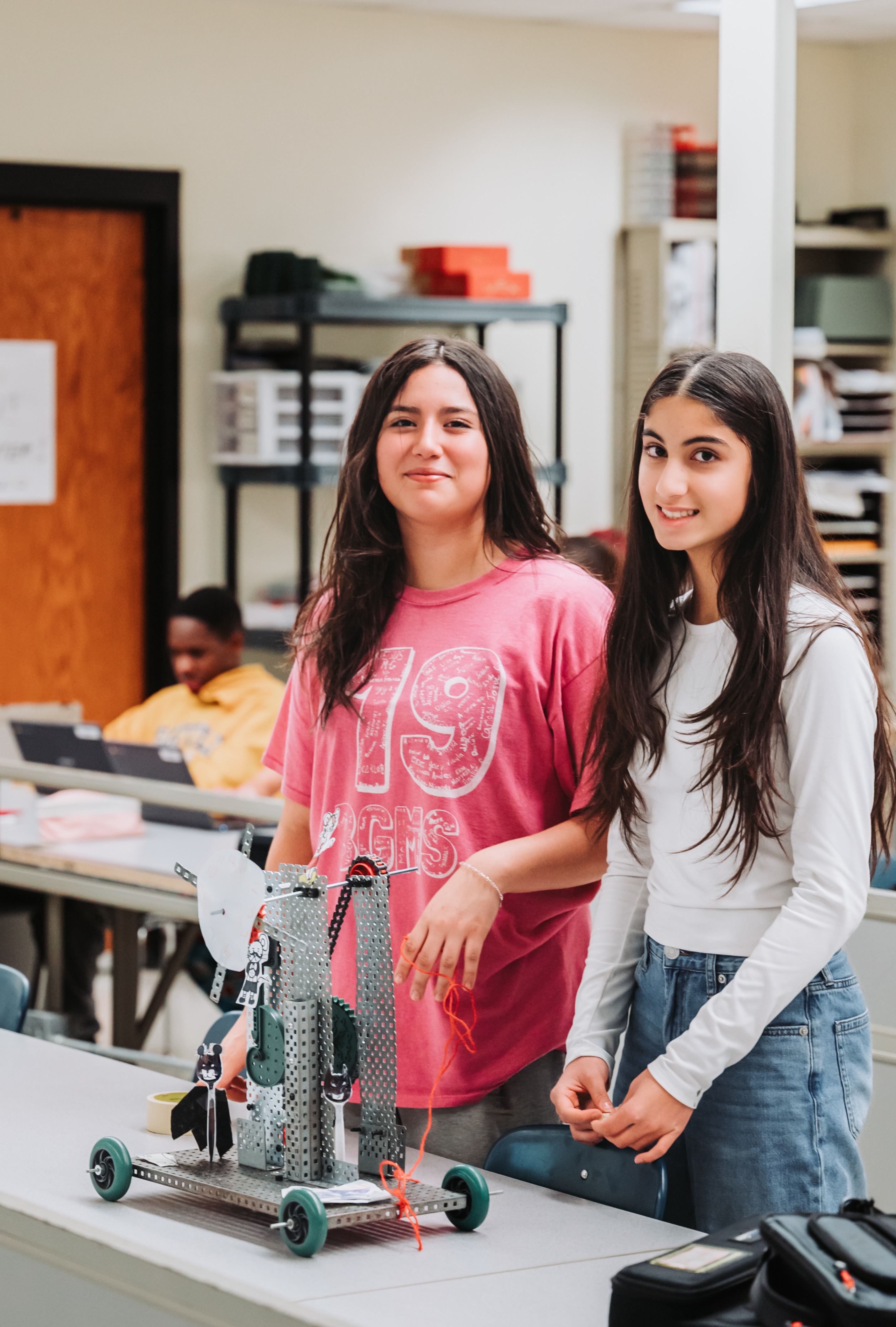 Two students stand with Robot that they made.