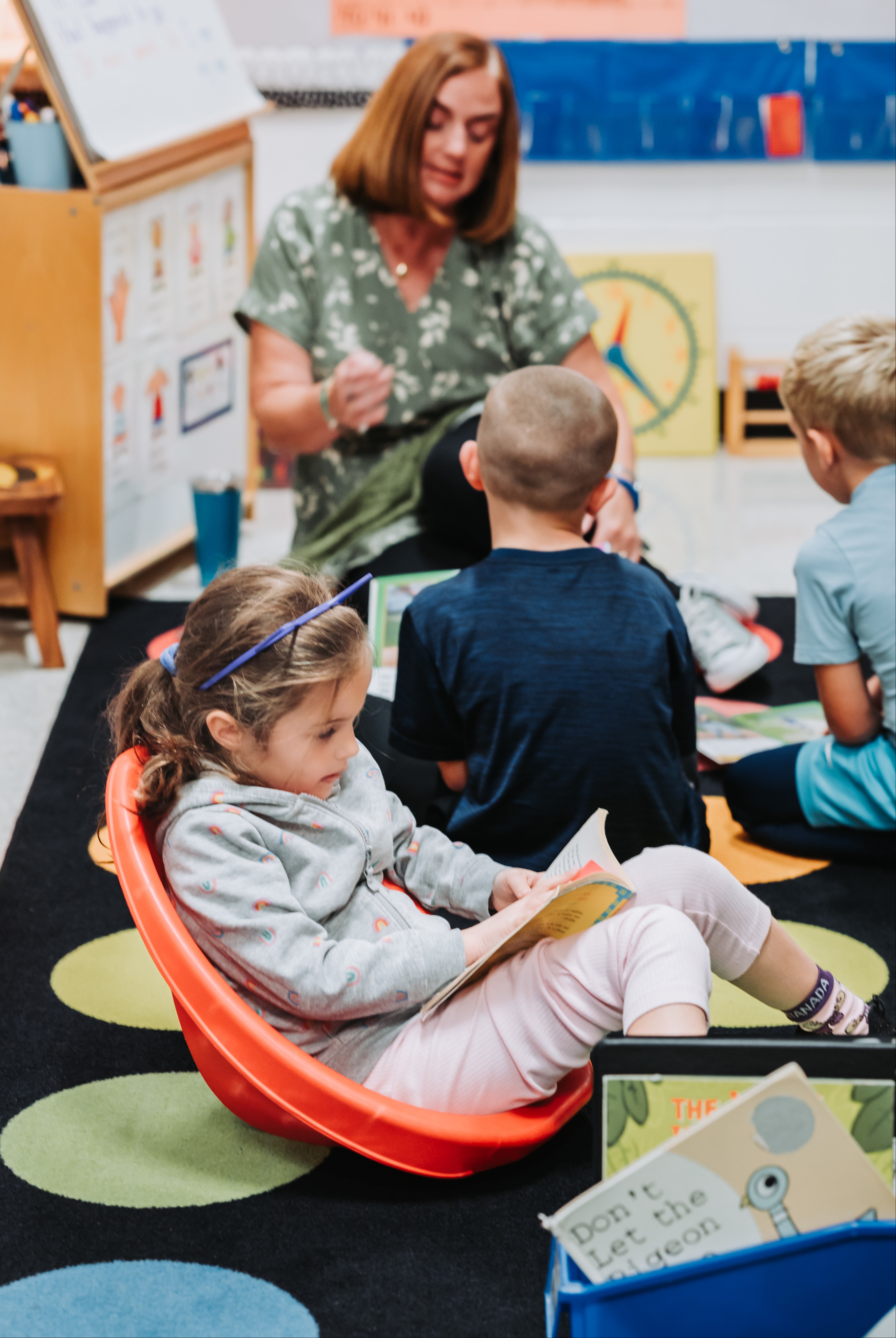 Three students read while two listen to a teacher and one reads independently.