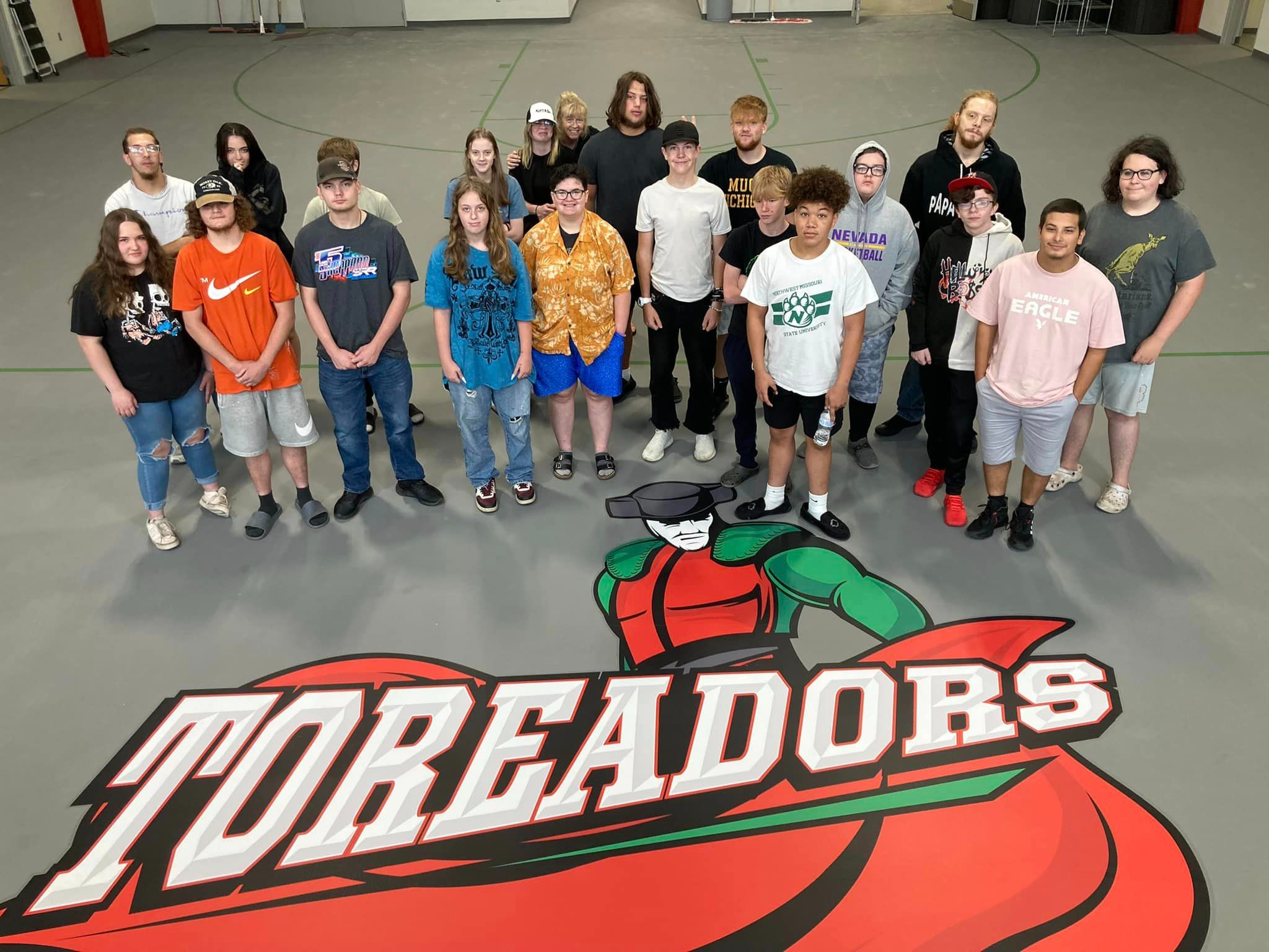 Students standing in a gym above the school toreador logo sign 