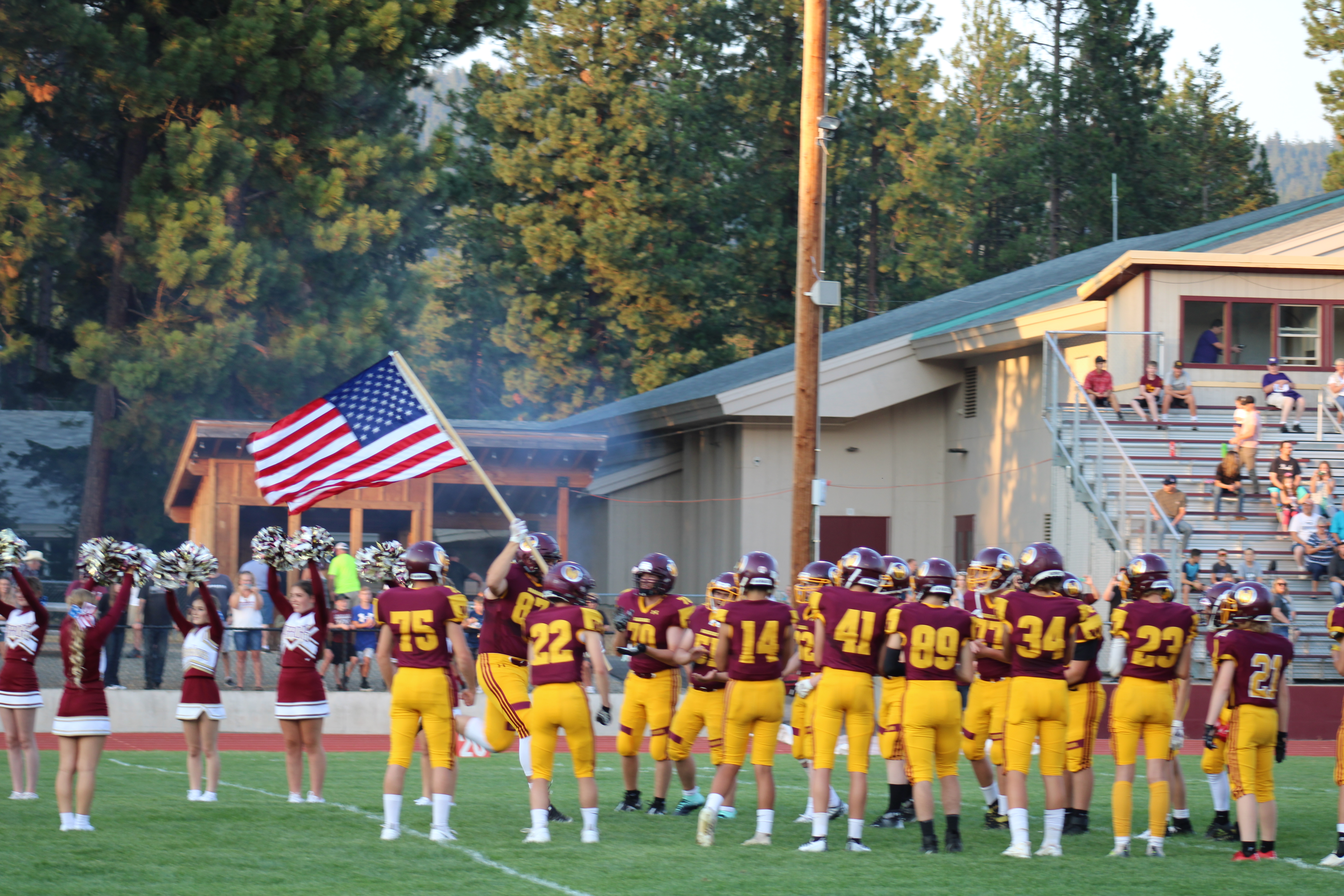 Football players taking the field for the first game carrying an American flag.