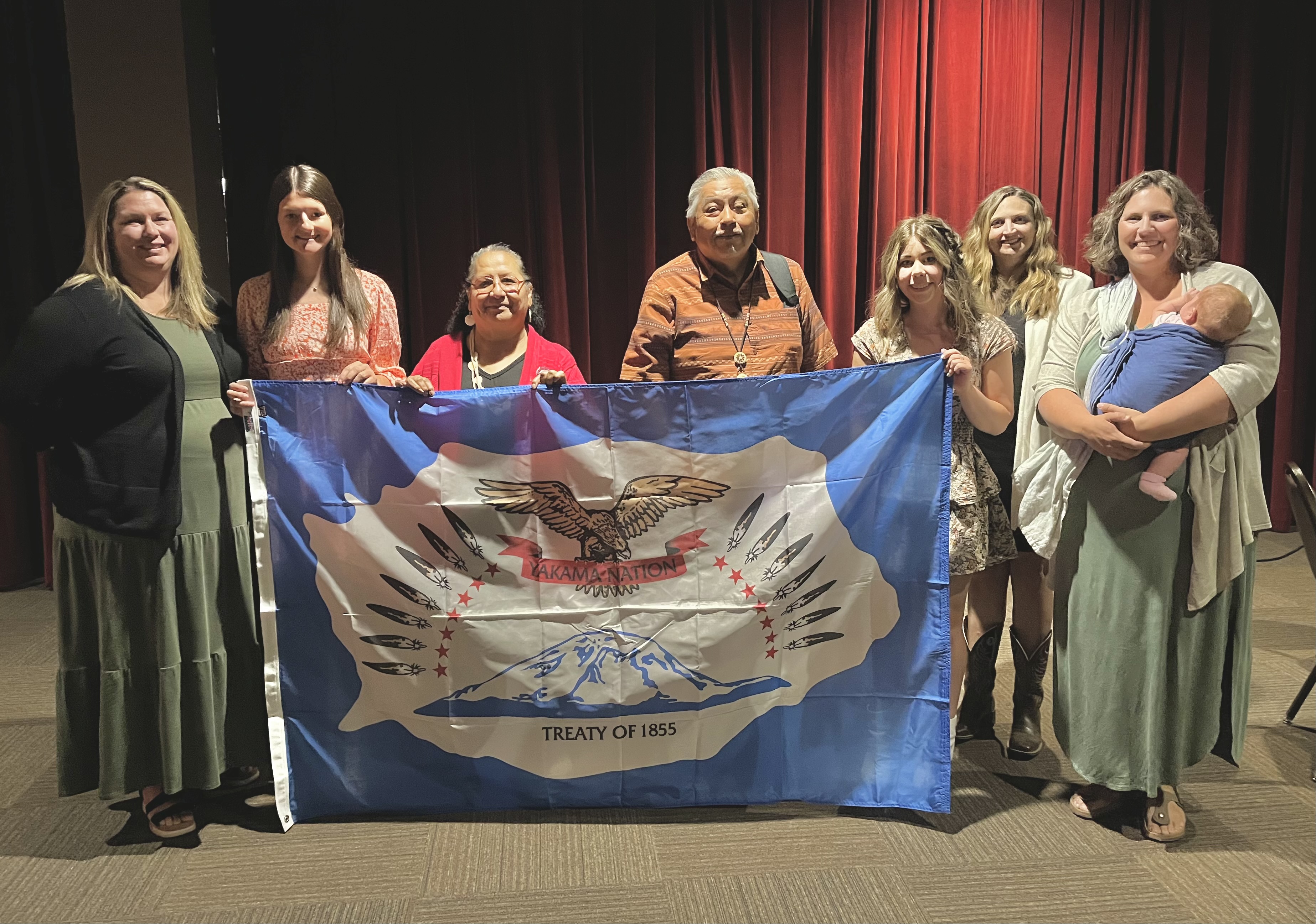 CERSD students, staff and board member standing with Arlen Washines holding the Yakama Nation  flag that was presented during Tribal Council. 