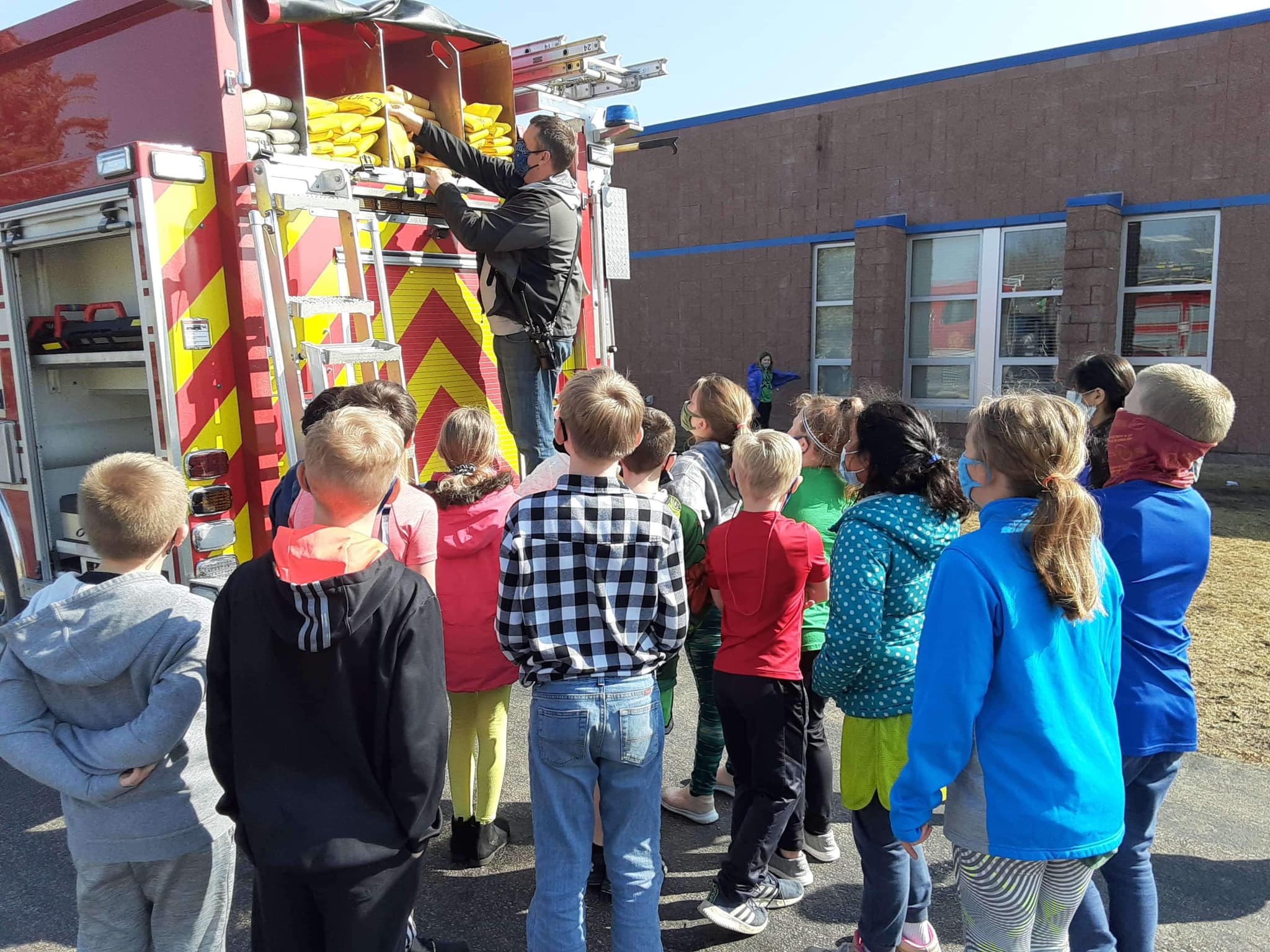 Students looking at someone on a firetruck