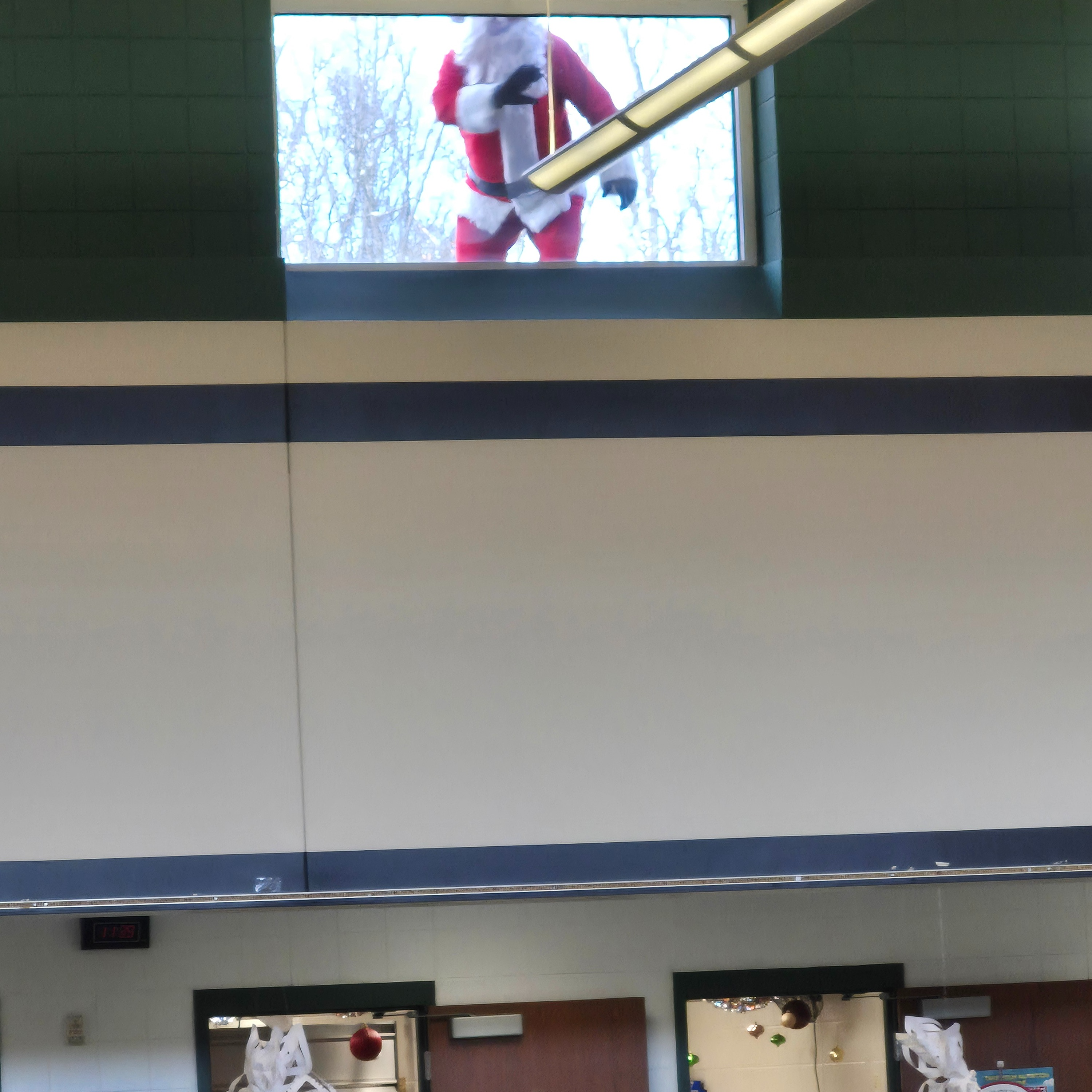 Person dressed as Santa peers through high cafeteria window.