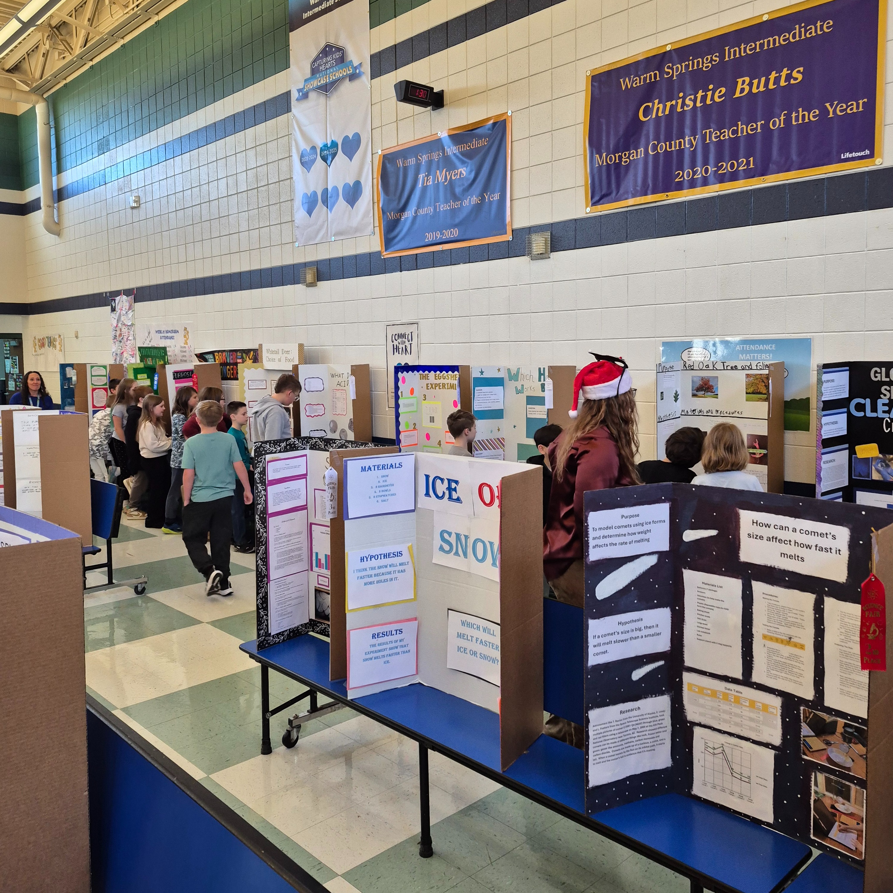Students view science fair projects displayed in a school gymnasium