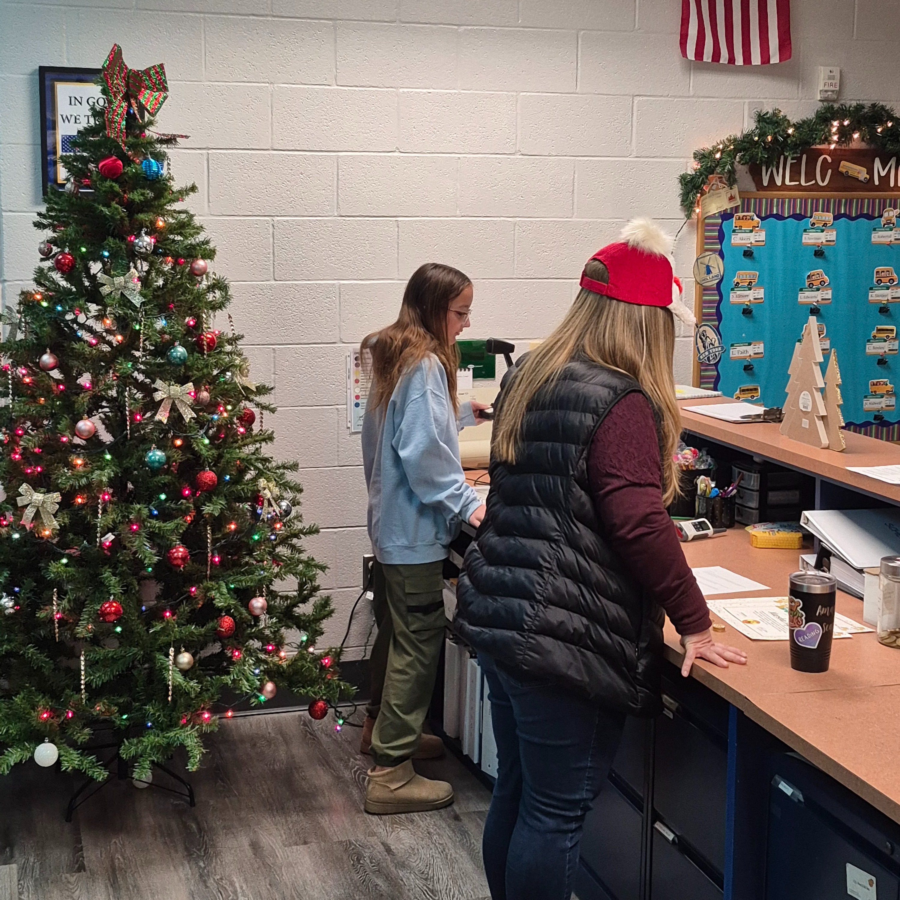 Student checks in at school office beside a decorated Christmas tree