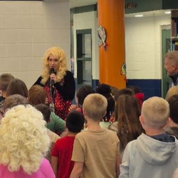 Staff member dressed as Dolly Parton speaks to a group of scholars.