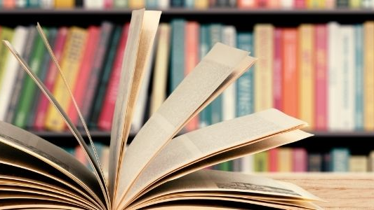 Picture of a wall of books with a book on the table opened up