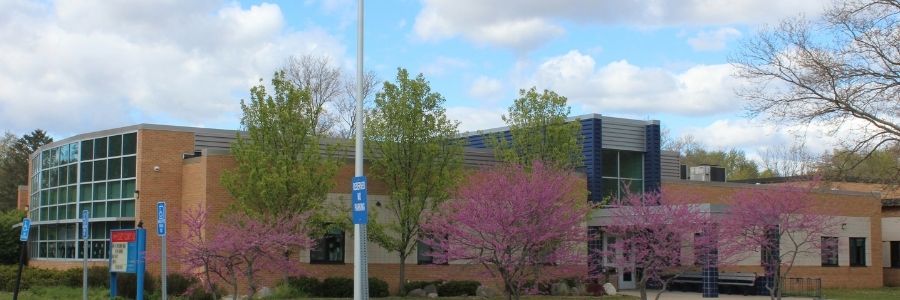 Picture of exterior of Gilkey Elementary with entrance to building, pink flowering tree and blue skies