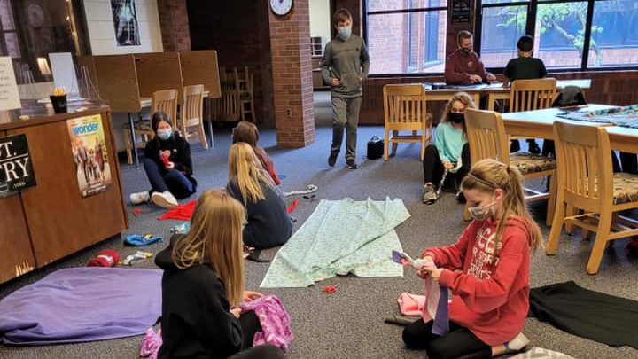 Students in library making fleece blankets for the community.