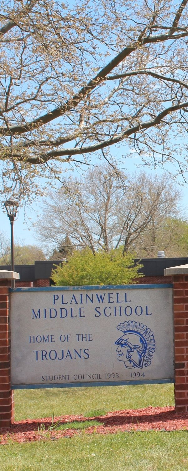 Picture of front entrance at Plainwell Middle School with sign out front with "Plainwell Middle School - Home of the Trojans"