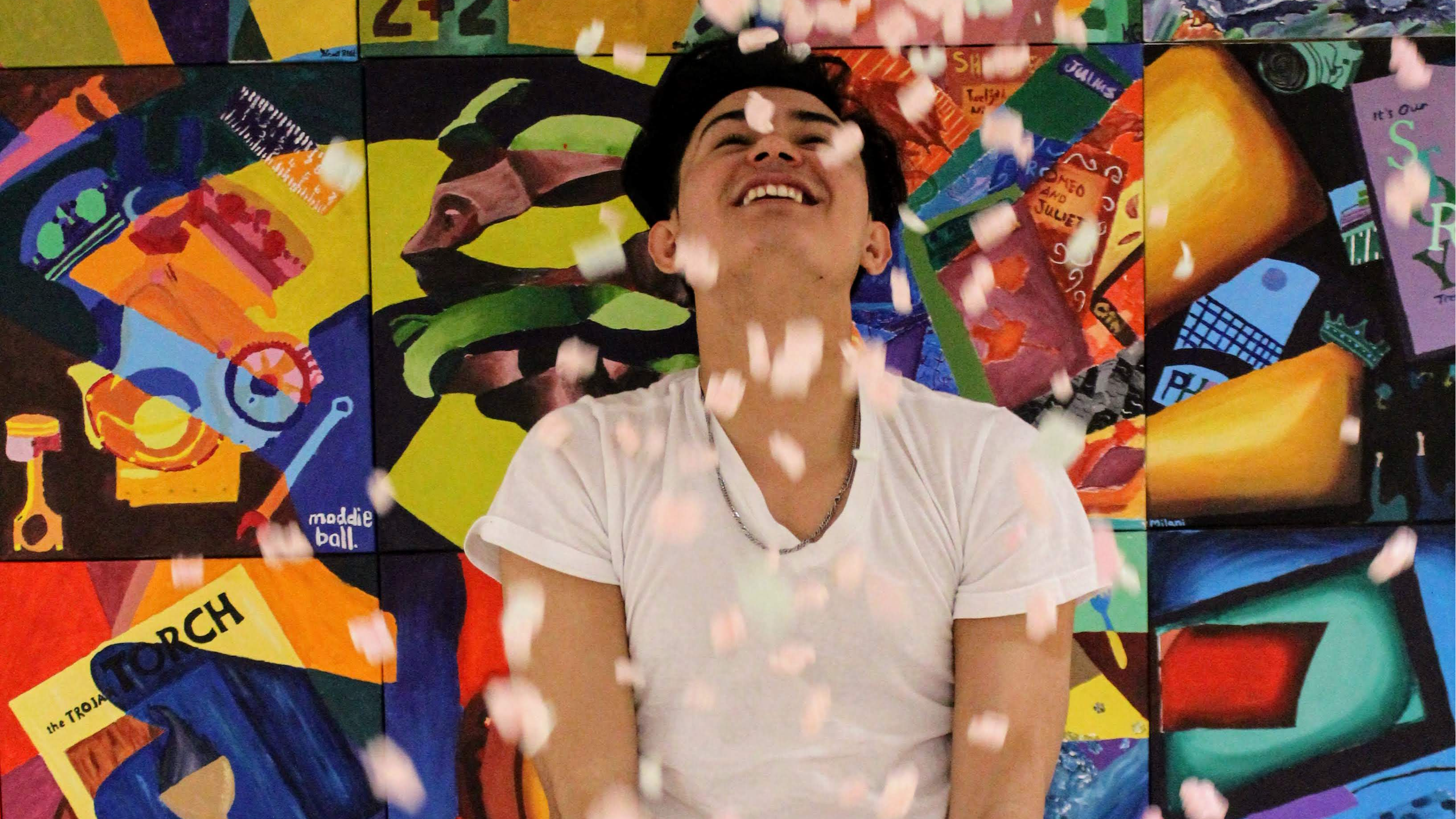 Picture of student throwing confetti in front of a color backdrop