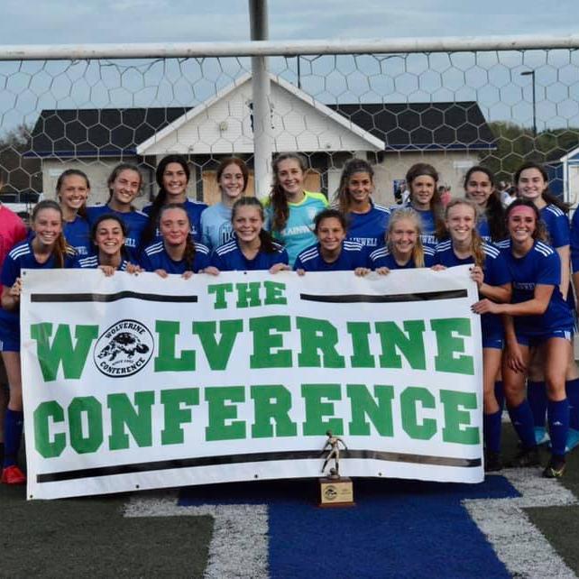Picture of women's soccer team holding a Wolverine Conference banner