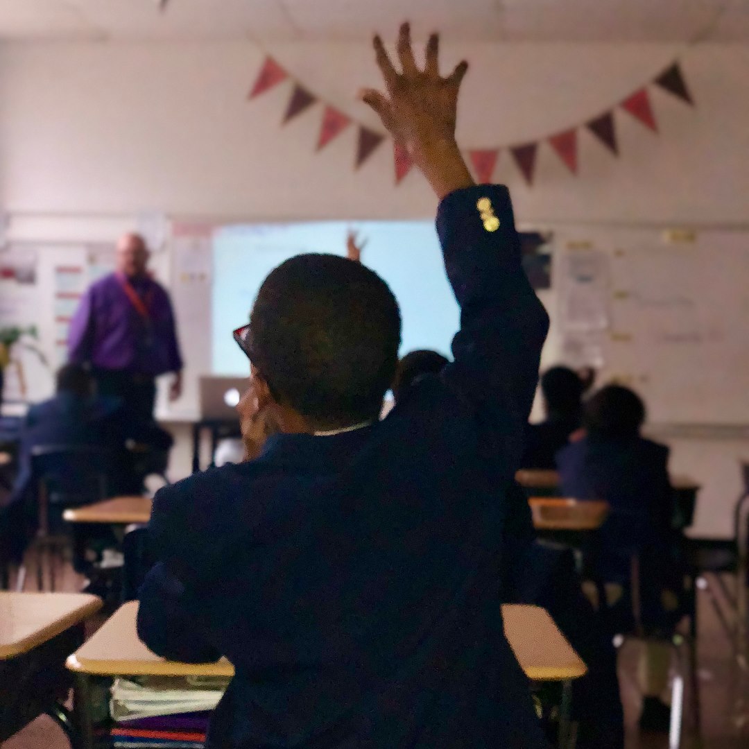 A student raises his hand in the classroom