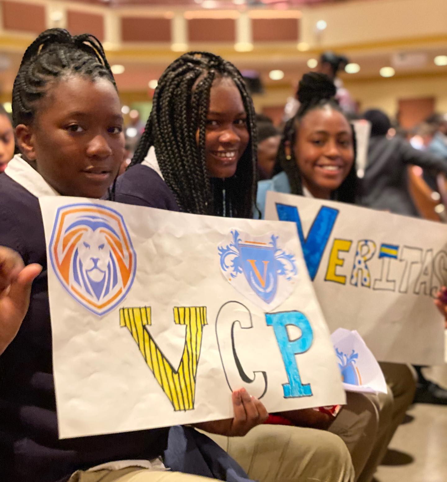 Students smiling and posing in auditorium with hand made VCP signs