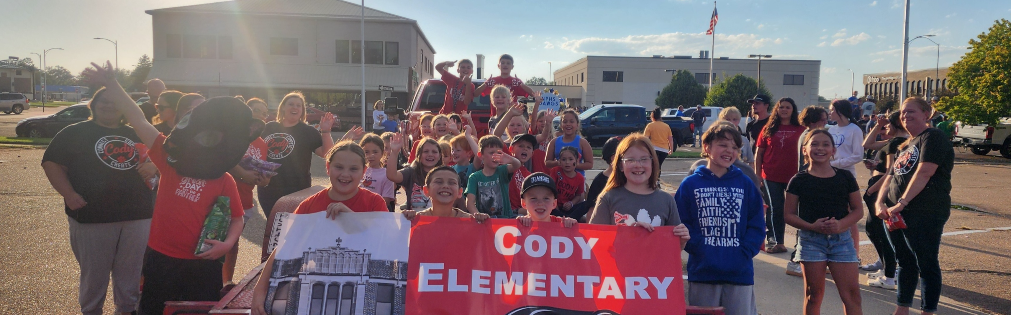 This is a picture of Cody Elementary students, families, and staff at the homecoming parade holding the Cody Elementary banner.