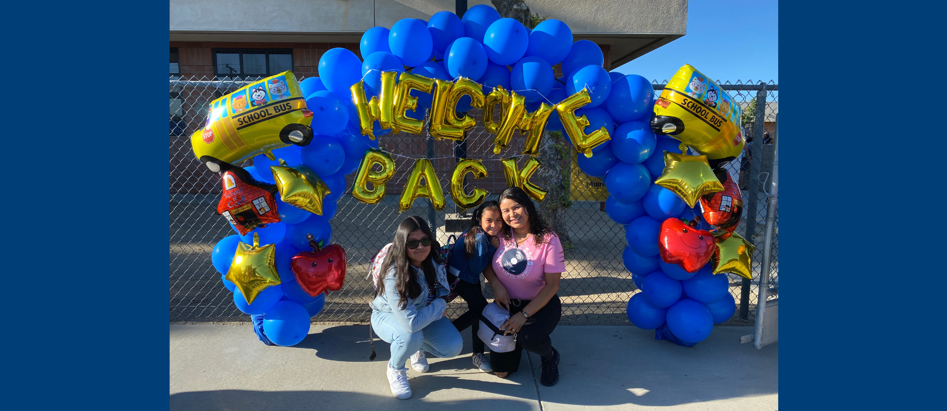 Family smiling in front of fun welcome back balloons