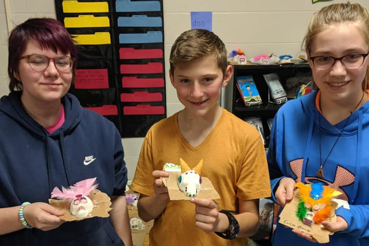a photo of students holding up art projects