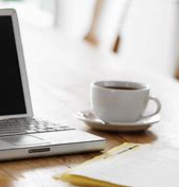 Coffee cup next to a laptop