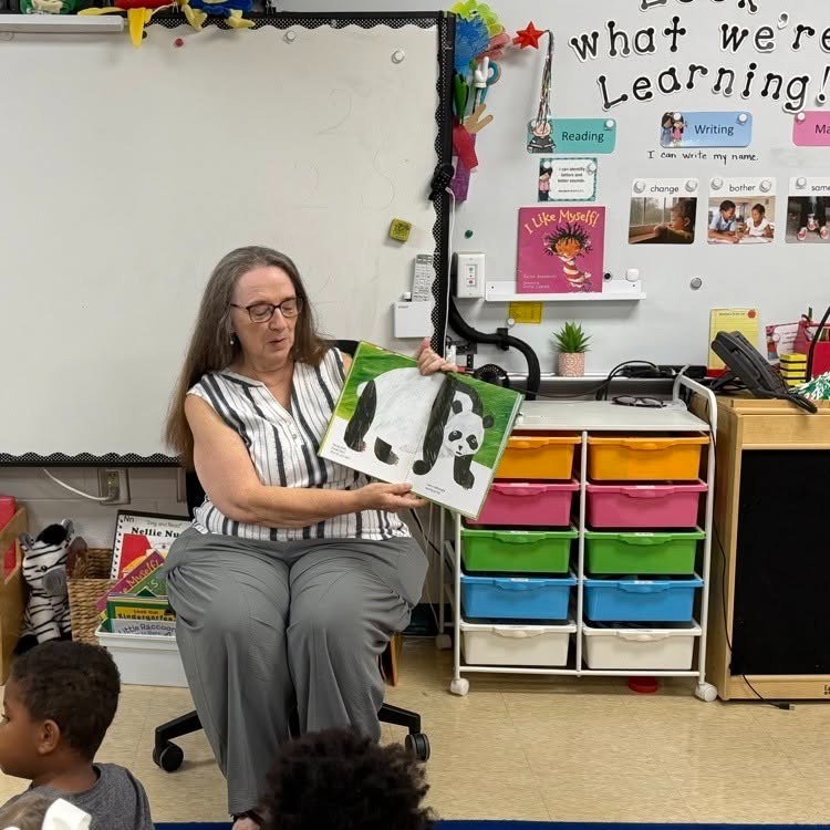 Real Grandparents Read to a first grade class holding a book with a giant panda
